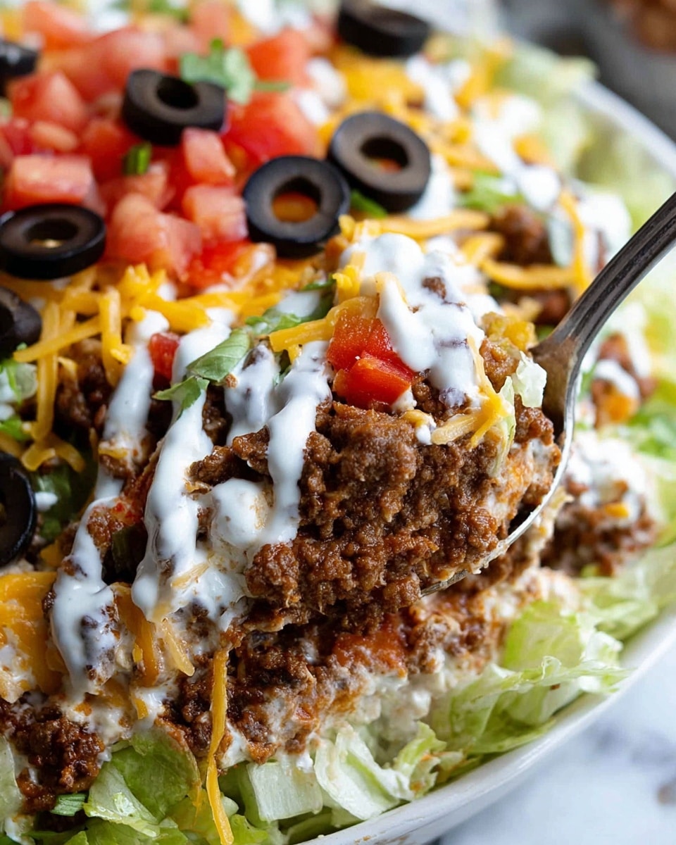 This close-up image shows a layered taco dip served in a white bowl, set on a white marbled surface. The bottom visible layer is chopped lettuce in light green, topped with a thick layer of crumbly browned ground beef mixed with small pieces of red bell pepper. On top of the beef rests a creamy white sauce, drizzled unevenly, followed by shredded cheese with bright yellow and orange tones sprinkled over it. Sliced black olives with smooth texture and a glossy finish are scattered on the top, along with some more shredded lettuce and diced red tomatoes blurred in the background. A silver spoon scoops a portion of the dip, highlighting the different layers and textures. Photo taken with an iphone --ar 4:5 --v 7