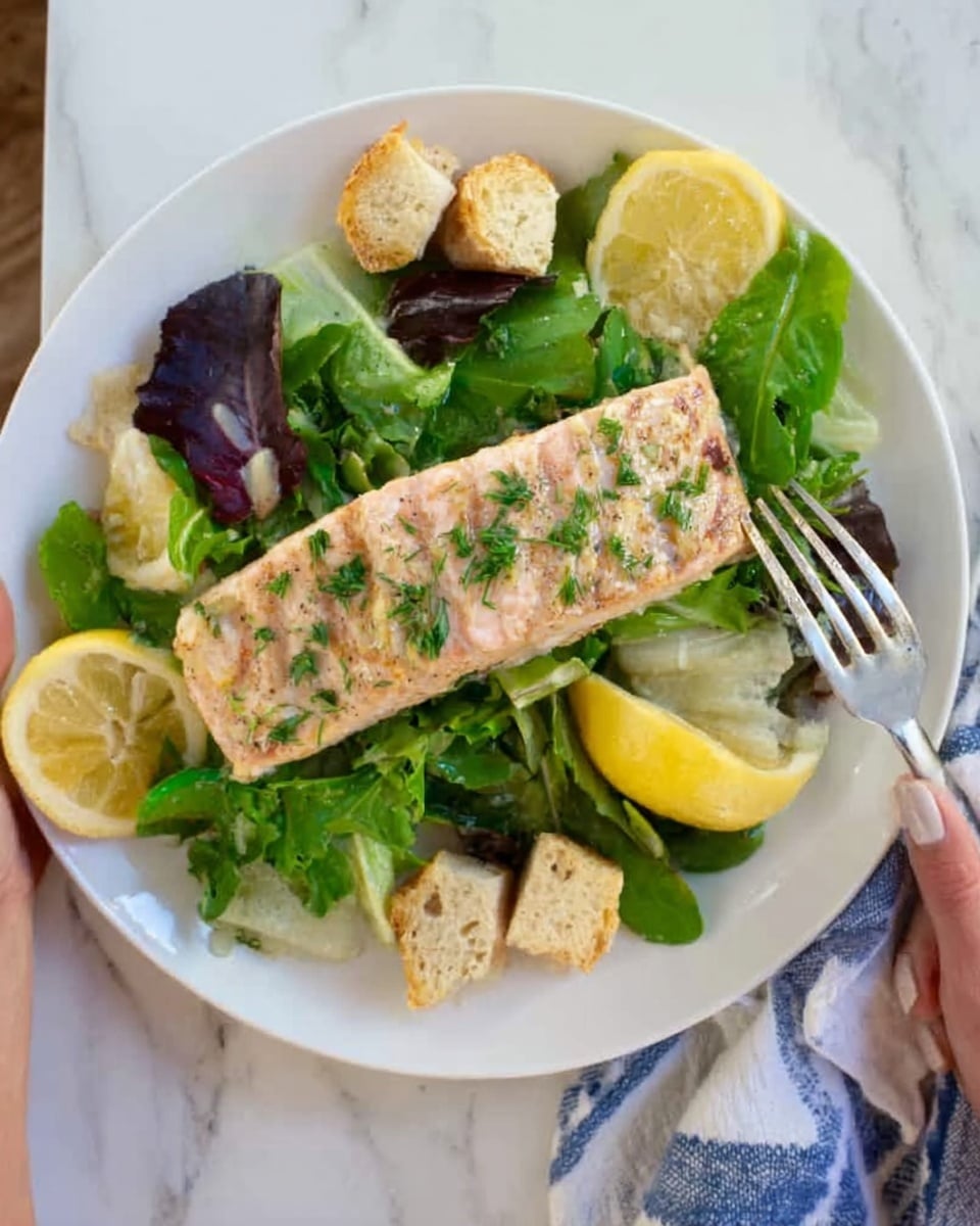 A white plate sits on a white marbled surface, holding a fresh salad topped with a large piece of grilled salmon. The salmon is light pink with grill marks and sprinkled with green herbs. Beneath the salmon, there are dark green leafy greens, and around the salmon, there are several pale yellow lemon wedges and small pieces of light beige toasted bread. A woman's hand is holding a fork near the plate. Photo taken with an iphone --ar 4:5 --v 7