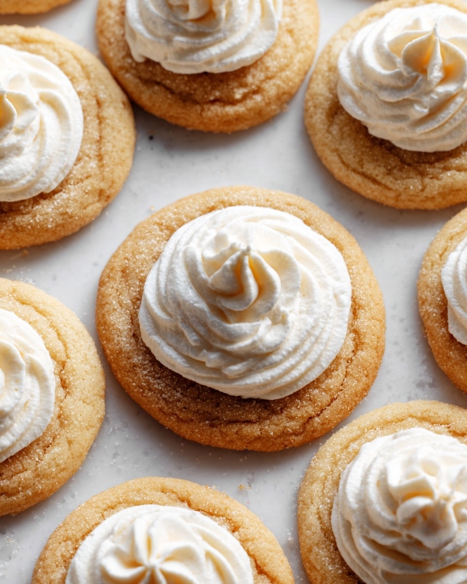 The image shows several round cookies placed close together on a white marbled surface. Each cookie has a light golden-brown base with a slightly rough texture. On top of the center of each cookie is a swirl of white cream, some with a smoother shape and others with a more peaked, whipped pattern. The cream looks soft and fluffy. The cookies are evenly spaced, and the lighting highlights their textures and creamy swirls clearly. Photo taken with an iphone --ar 4:5 --v 7