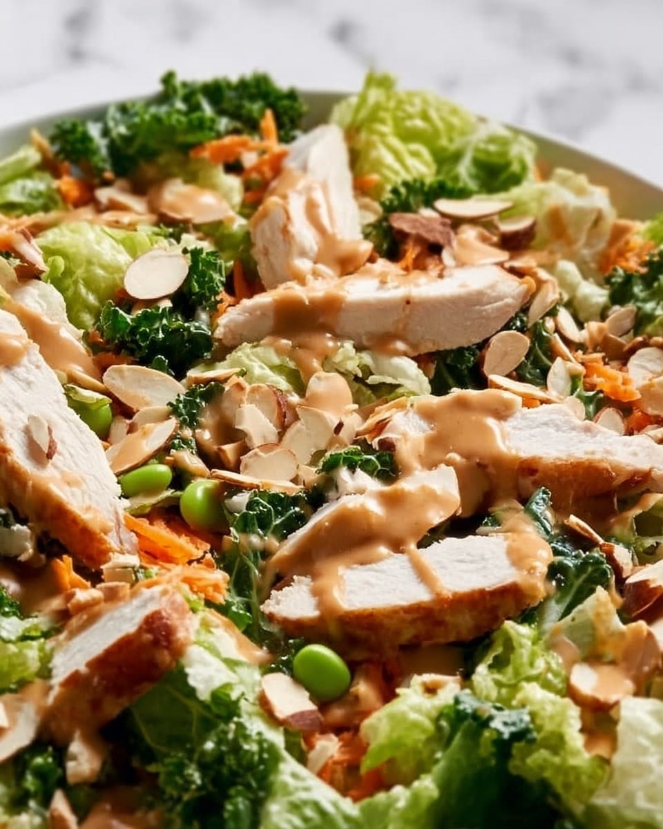 The image shows a close-up of a salad arranged in a white bowl, sitting on a white marbled surface. The salad has multiple layers: a base of light green lettuce leaves, mixed with thin carrot strips and pieces of bright green broccoli. On top, there are slices of cooked chicken, browned and juicy, scattered evenly. The salad is sprinkled with light beige almond slices and small green edamame beans. A creamy brown dressing is drizzled over the entire salad, adding a glossy texture and rich color contrast. Photo taken with an iphone --ar 4:5 --v 7