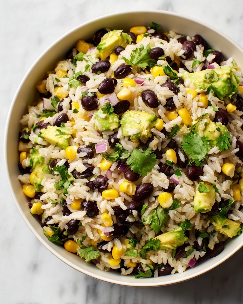A close-up image of a bowl filled with a colorful rice salad featuring white long-grain rice as the base mixed with black beans, bright yellow corn kernels, diced green avocado, chopped red onion, and small green herb pieces, all combined evenly to create a textured, vibrant mix. The bowl is white, placed on a white marbled surface, and a few sprigs of fresh green herbs are visible on the side inside the bowl. The overall look is fresh and lively with a neat, casual presentation. photo taken with an iphone --ar 4:5 --v 7