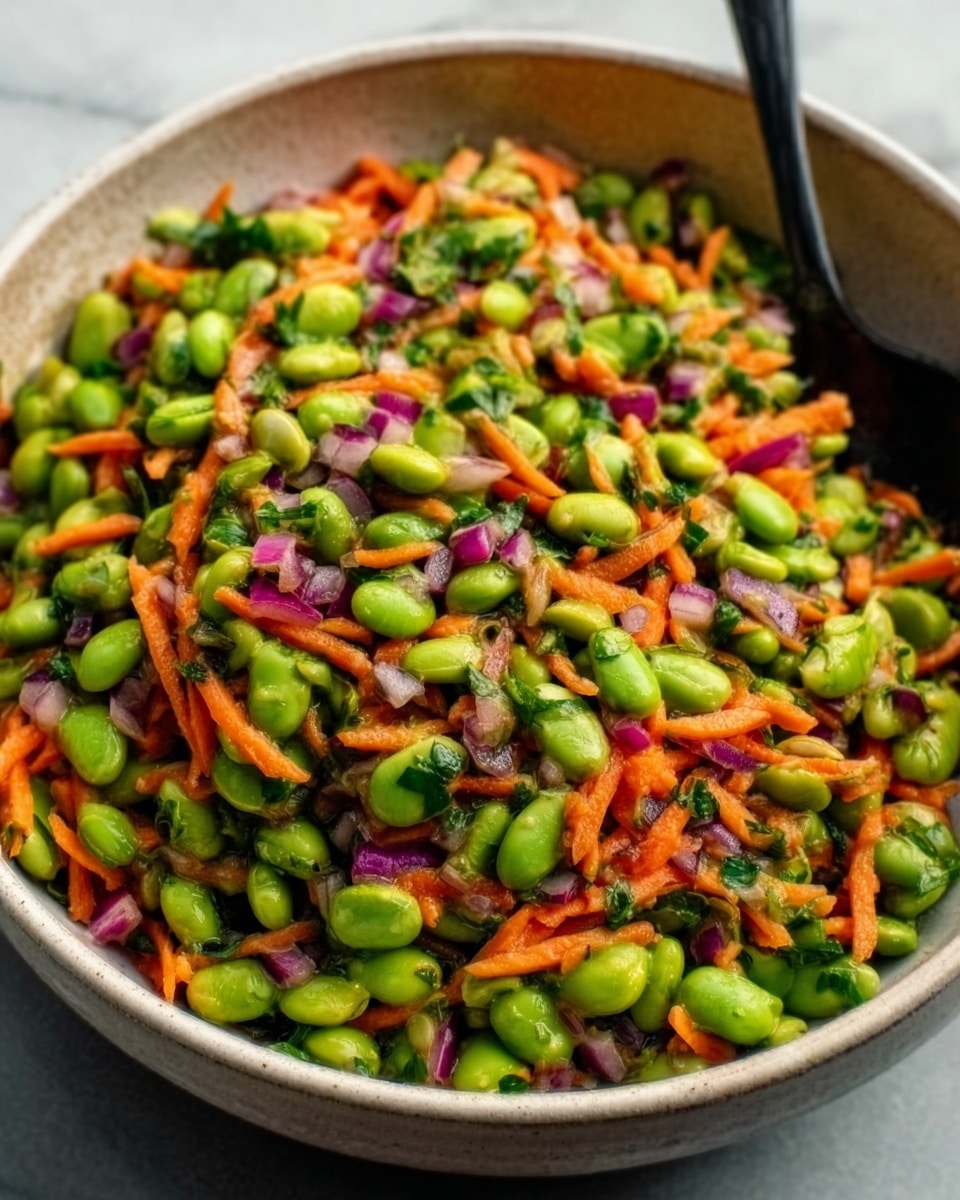 A close-up of a large white bowl filled with a colorful mixed salad made of edamame beans, shredded carrots, chopped red onions, and finely chopped green herbs. The salad layers show a variety of bright colors: light green from the edamame, orange from the carrots, purple from the onions, and small green bits of herbs scattered throughout. A black spoon is placed on the right side inside the bowl, partially dipped in the salad. The bowl is set on a white marbled surface. photo taken with an iphone --ar 4:5 --v 7