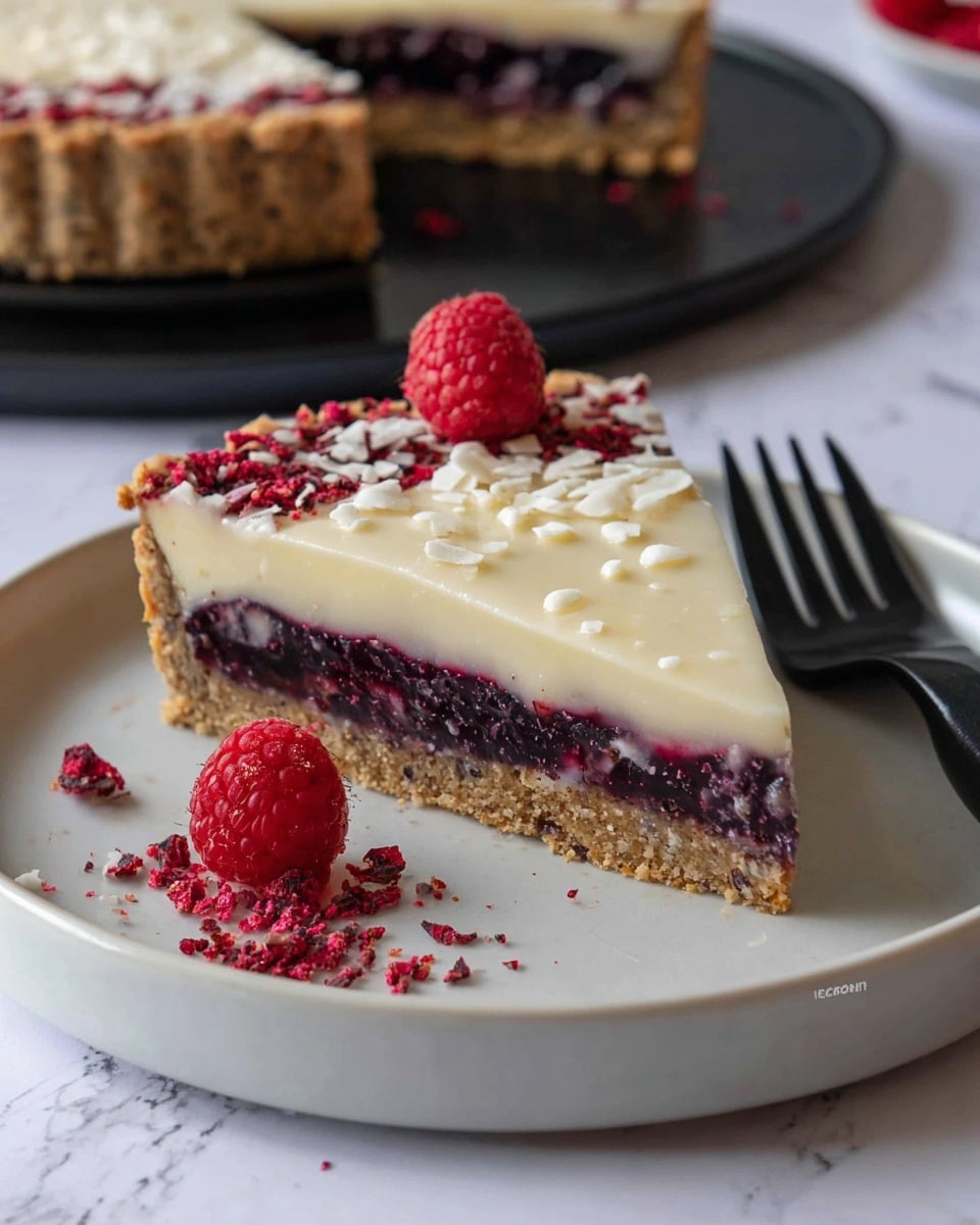 A slice of tart with three layers sits on a white plate: the bottom layer is a light brown crumbly crust, the middle layer is a thick dark purple berry filling with a somewhat chunky texture, and the top layer is a smooth, pale cream-colored custard sprinkled lightly with white flakes. The tart slice is accompanied by a fresh red raspberry next to it, and a dark purple blackberry behind it. A black fork rests on the plate near the slice. In the background, the remaining tart with the same layers is placed on a white plate on a white marbled surface, decorated with a single raspberry on top and scattered small red crumbs around it. photo taken with an iphone --ar 4:5 --v 7