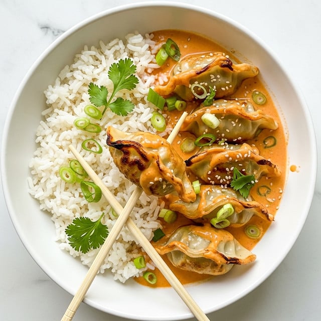 A white bowl shows a dish with two main layers: on the right, a pile of fluffy white rice with separate grains, and on the left, three golden-brown dumplings covered in a thick orange creamy sauce. The dumplings have a slightly crispy edge and are sprinkled with green onion slices and white sesame seeds. There is also some fresh cilantro on top and around the dumplings. A pair of wooden chopsticks holds one dumpling gently at the center. The background is a white marbled texture. photo taken with an iphone --ar 4:5 --v 7