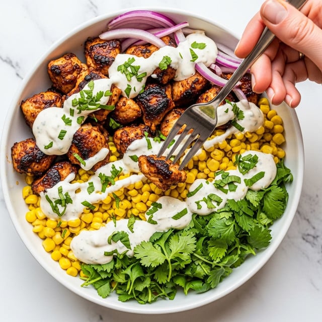 The image shows a bowl filled with several layers: the bottom layer is bright yellow corn mixed with fresh green cilantro leaves, followed by chunks of dark brown grilled chicken with a slightly charred texture. There are thin slices of light purple onion scattered throughout. A creamy white sauce is drizzled generously over the chicken and corn, topped with more bits of chopped green herbs for garnish. A woman's hand holding a fork is picking up a piece of chicken, adding dynamic action to the image. The bowl is white, and the background is a white marbled texture. photo taken with an iphone --ar 4:5 --v 7