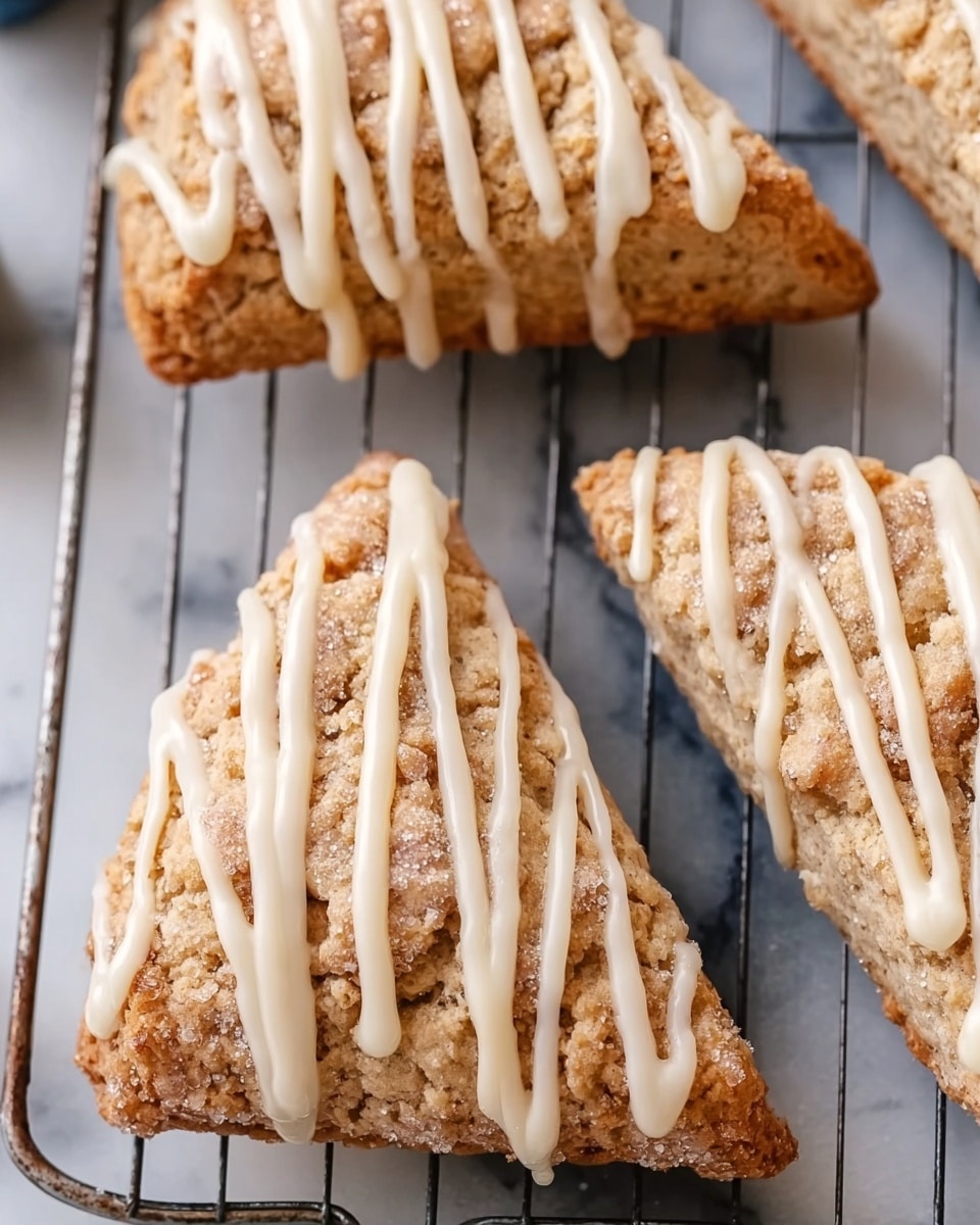 The image shows three triangular scones with a light brown, crumbly texture, dusted with fine sugar, arranged on a metal cooling rack. Each scone is decorated with creamy white icing in zigzag lines running from the wide end to the narrow tip, creating a contrast with the slightly rough surface of the scones. The metal cooling rack sits on a white marbled surface, adding a clean background to the warm tones of the baked goods. photo taken with an iphone --ar 4:5 --v 7