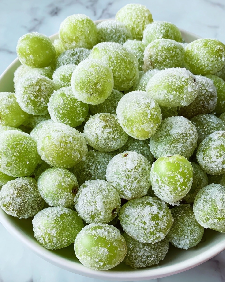 A close-up view of a white bowl filled with many light green grapes, each grape fully covered in a layer of white sugar crystals giving them a frosted look, all piled high and tightly packed together, set on a white marbled textured surface. photo taken with an iphone --ar 4:5 --v 7