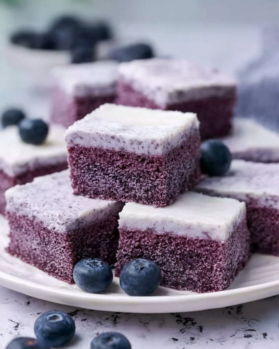The image shows several square pieces of soft purple cake stacked on a white plate. Each piece has two layers: a thick, moist purple cake base with a slightly grainy texture, and a thin, smooth white icing layer spread on top. The cakes are arranged closely together with some fresh blueberries scattered on the white marbled surface around the plate. The background is softly blurred, keeping the focus on the layered cakes. Photo taken with an iphone --ar 4:5 --v 7