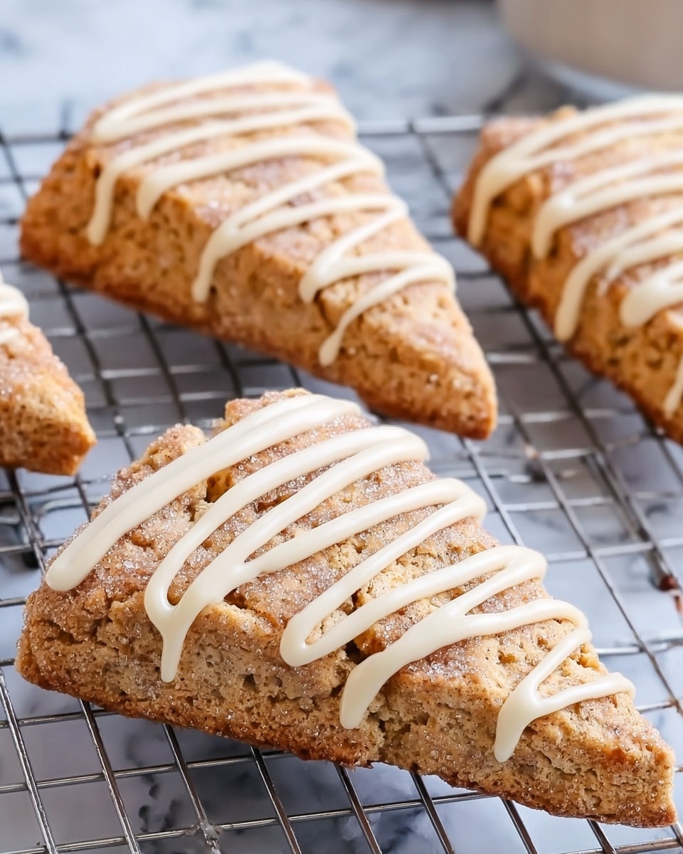 The image shows several triangular scones placed on a metal cooling rack with a white marbled surface underneath. Each scone has a rough, crumbly light brown texture dusted with sugar on top. On top of this sugar-coated scone layer, there are thick white icing lines drizzled in horizontal zigzags from one end to the other. The scones are arranged closely but not touching, and the pattern of icing adds a soft contrast to the rough scone texture. Photo taken with an iphone --ar 4:5 --v 7