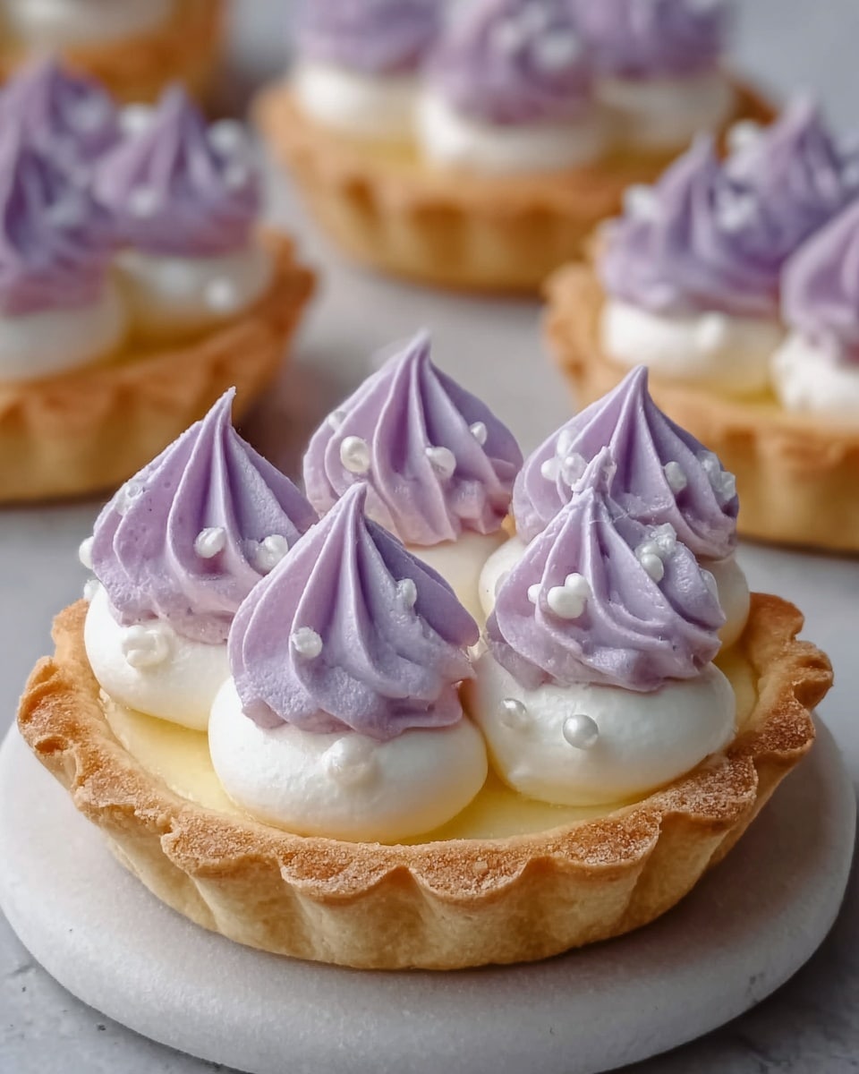 A small tart with a golden, flaky crust forms the base, filled with a smooth, creamy layer of white filling. On top, there are swirls of light purple and white whipped cream arranged evenly in a circle. In the center of the tart are small purple flower petals adding a delicate touch. The tart sits on a white plate placed on a white marbled surface. photo taken with an iphone --ar 4:5 --v 7